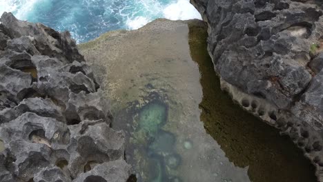 Aerial-overhead-flight-over-famous-natural-pools-named-Devil's-Billabong-on-Nusa-Penida,Bali