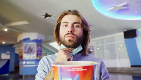 man in a mask watching a movie in a theater