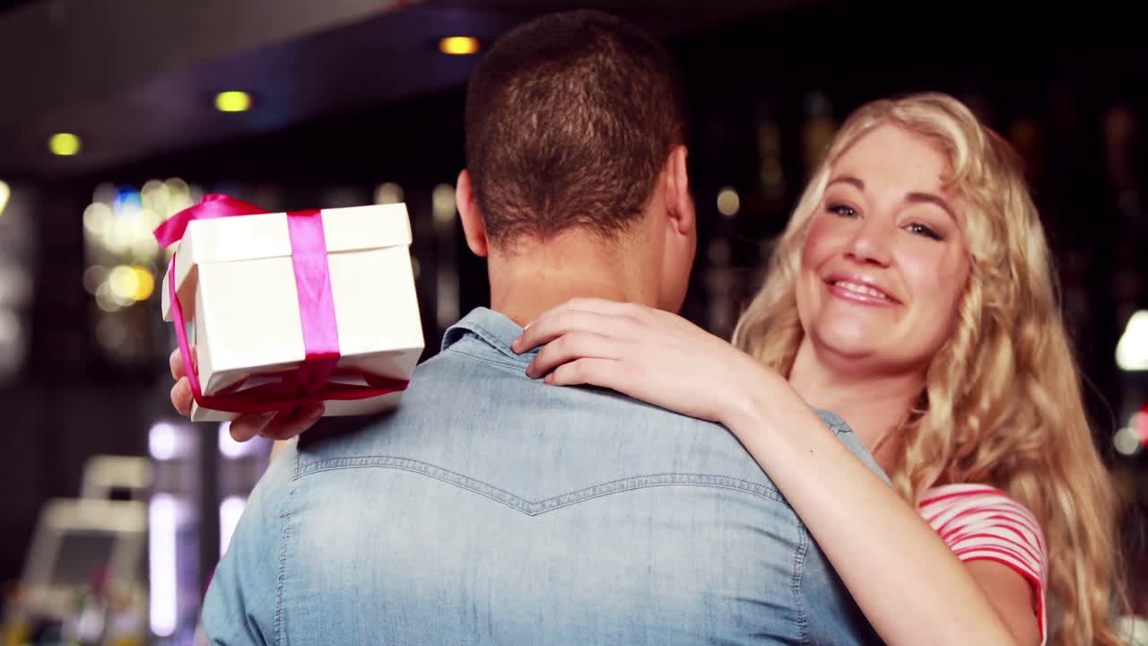 una joven pareja abrazándose con un regalo