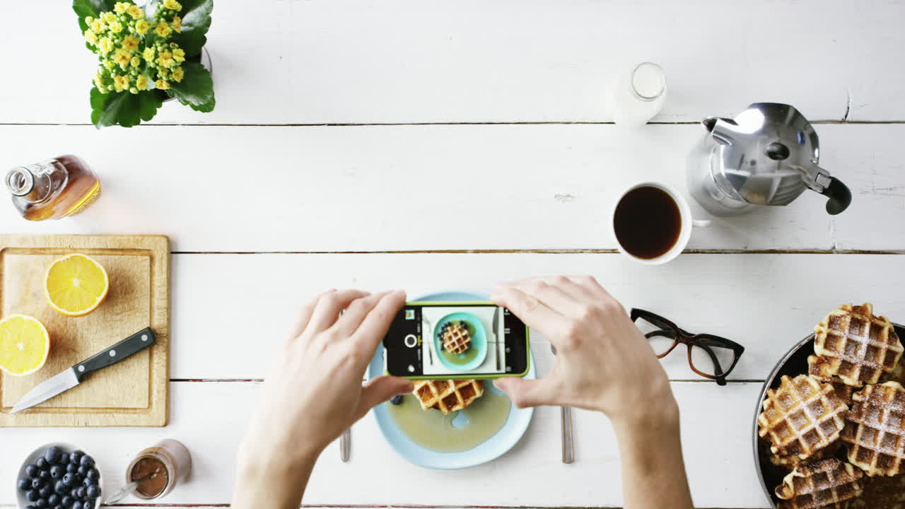 vista superior hombre fotografiando el desayuno usando teléfono móvil gofres belgas y manos de café desde arriba - dragón épico rojo