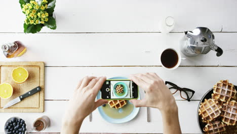 top view man photographing breakfast using mobile phone belgian waffles and coffee hands from above - red epic dragon