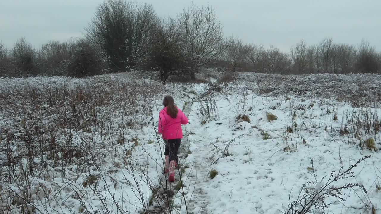 Slow motion child running away in snow field
