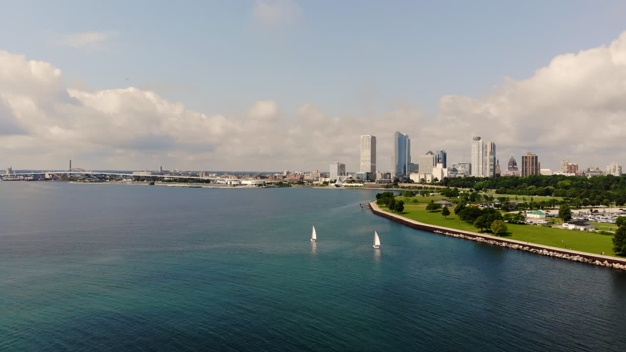 panorámica aérea de veleros en una bahía tranquila con el horizonte de la ciudad en el fondo