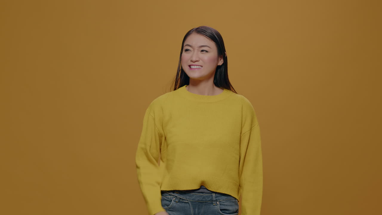 Athletic woman flexing arms muscles over yellow background