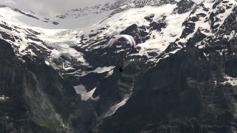 paraglider riding wind currents with alpine peaks in background