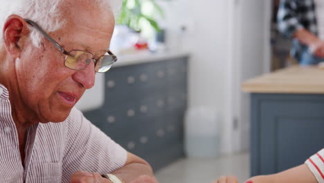 Grandad-and-grandson-drawing-together-in-kitchen,-close-up