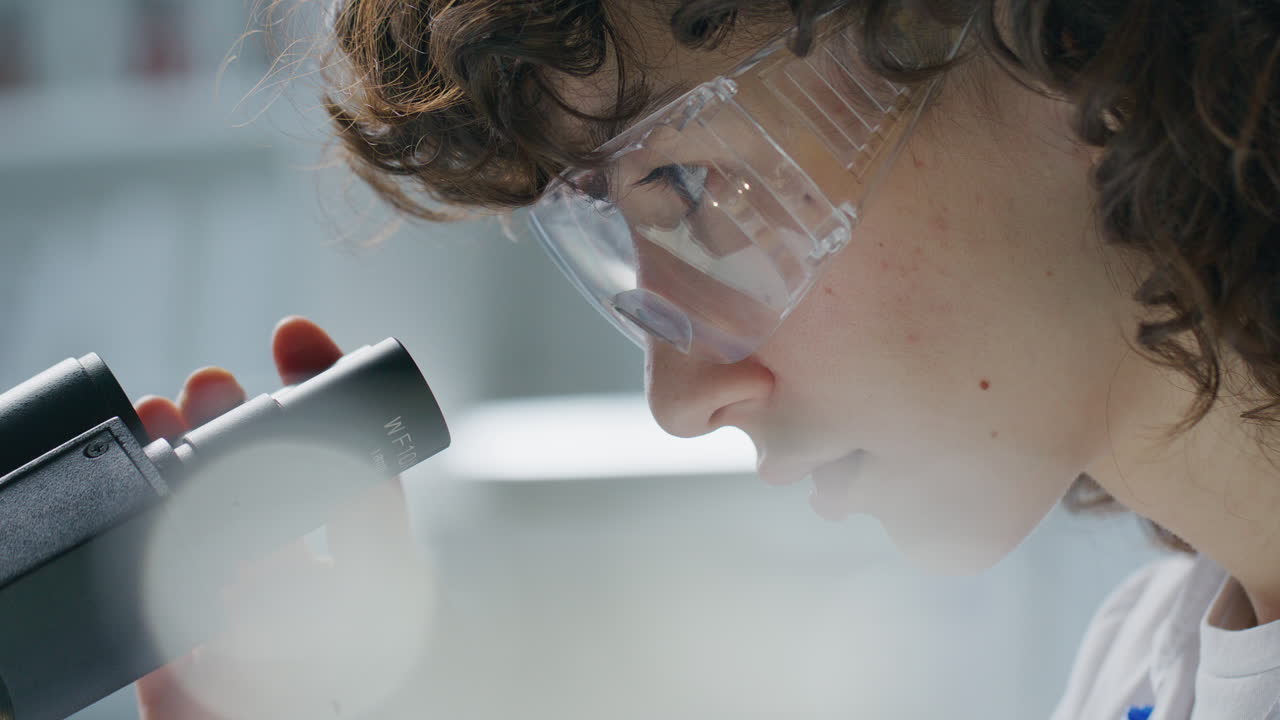 Focused Female Scientist Looking through Binocular Microscope in Laboratory