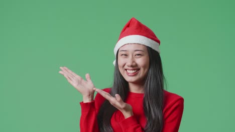 woman wearing a santa hat, smiling, and presenting something.