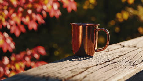 copper mug on wooden railing in autumn
