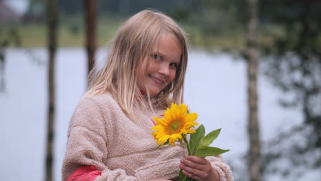 cute little girl holds sunflower in hand and smiles, portrait view