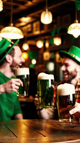 friends cheering with beer mugs in a pub on st. patrick's day