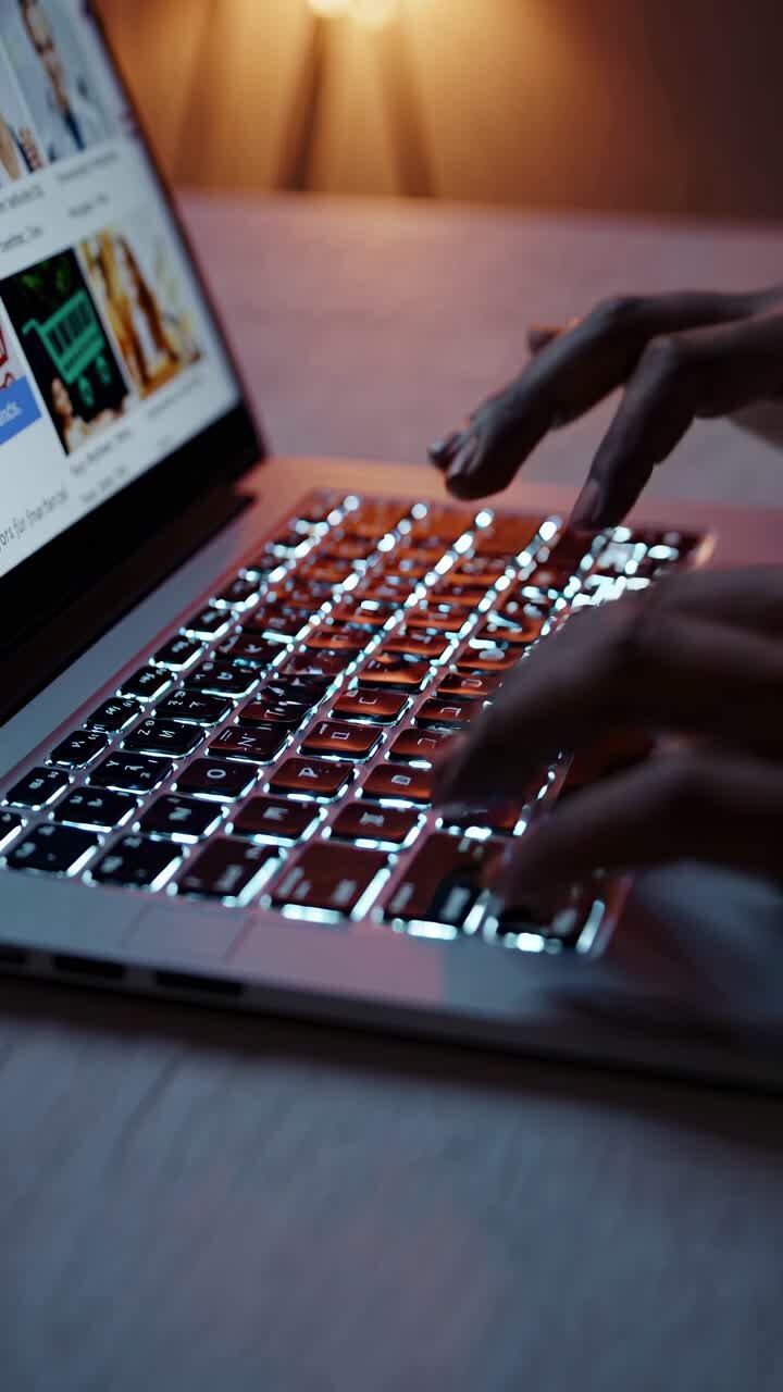 Nærbillede i lav vinkel af hænder, der skriver på et laptop-tastatur med en blødt oplyst baggrund