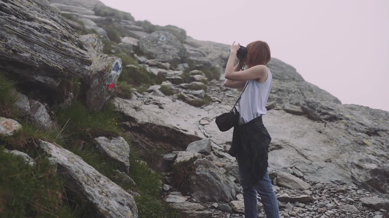 una joven excursionista sube montañas con una cámara fotográfica. transfagarasan, montañas de los cárpatos en rumania