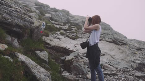 a young woman hiker climbs mountains with photo camera. transfagarasan, carpathian mountains in romania