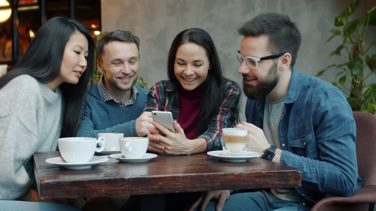 Friends enjoying coffee and using smartphone in a cafe