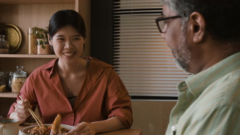 multi-ethnic couple or friends enjoying a meal together with chopsticks
