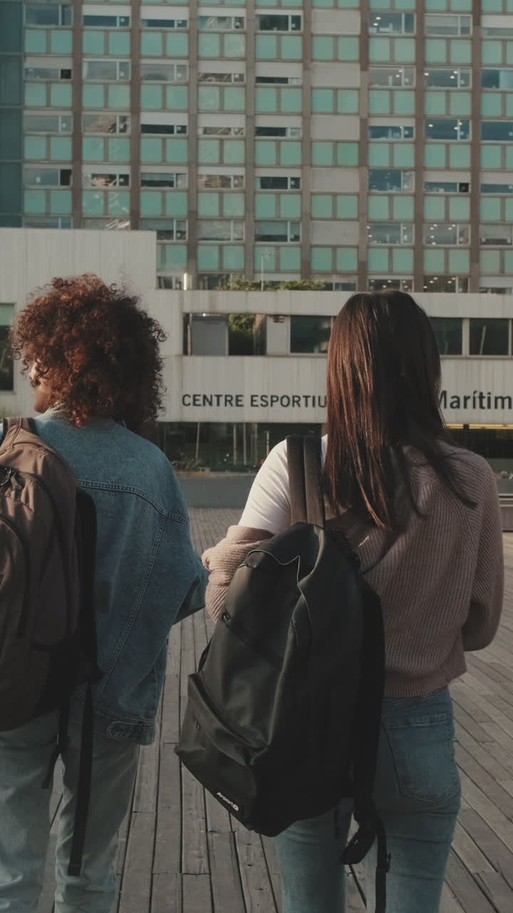 Two women with backpacks in front of a building