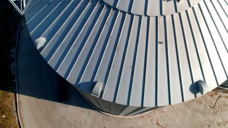 modern granary at sunlight. grain elevator. large silver container for agriproducts. close-up. view from above. camera moving in round.