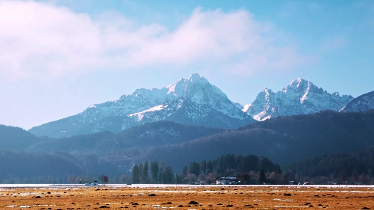 Auto che passa su una strada con una casa e montagne in lontananza, da qualche parte nel sud della Germania
