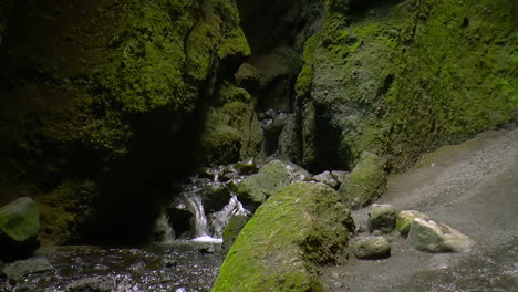 Dark-footage-of-small-river-stream-and-small-waterfalls-inside-cave---Raudfeldsgja-Gorge,-Iceland-on-Snaefellsnes-peninsula