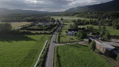 aerial view of car driving through a road in the middle of green valley, rendalen, norway