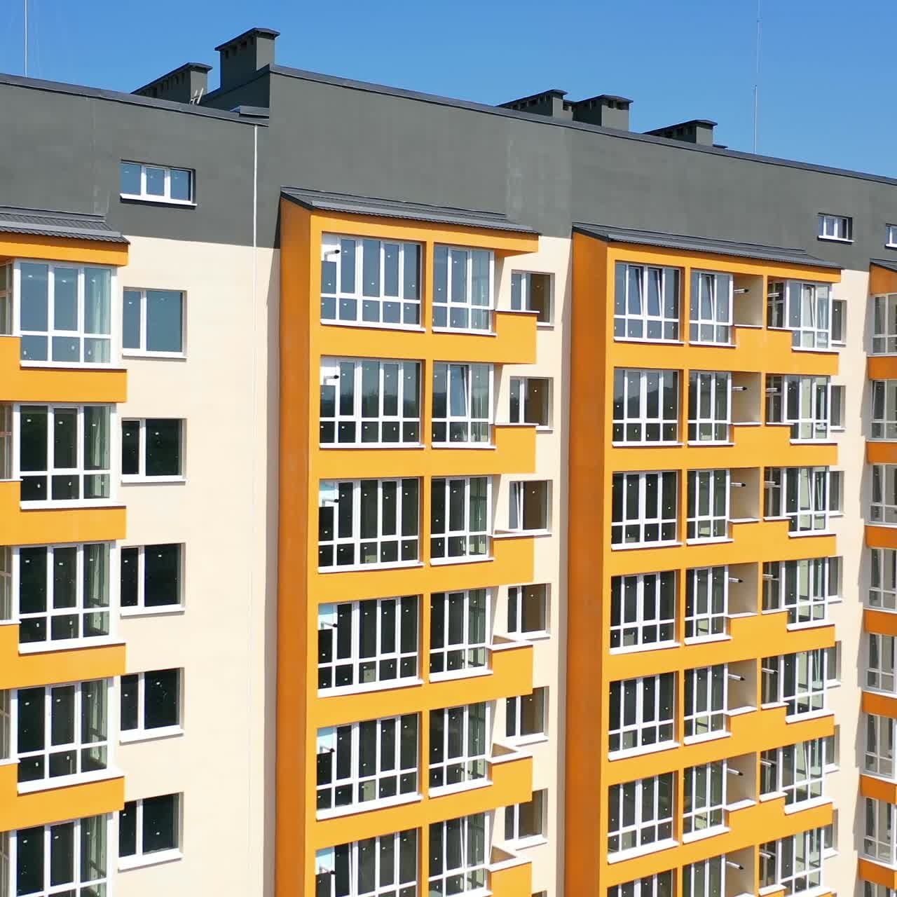 Facade of a new house for city residents. Modern apartment building with large windows and colorful walls in sunny summer day