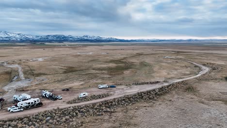 camping ground with motorhomes in remote plains with snow mountains in the background