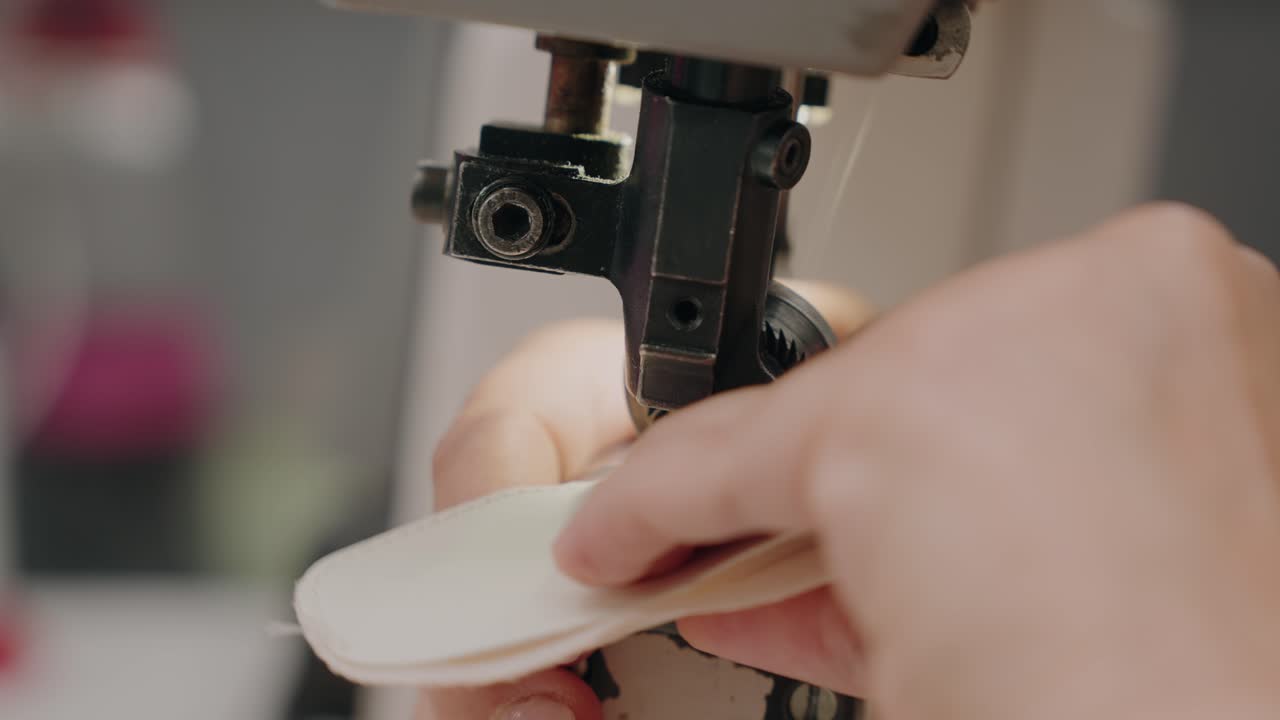 hands carefully guide leather as machine stitches shoe part with precision