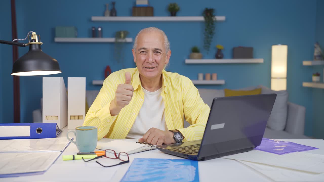 Home office worker old man making positive gesture at camera.