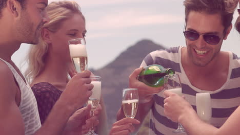 happy friends celebrating with champagne by the pool