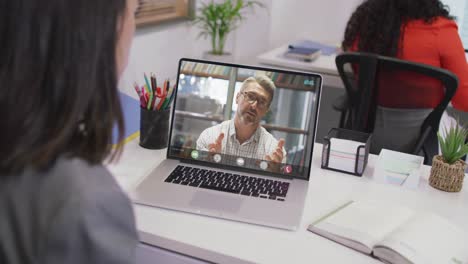 Biracial-businesswoman-using-laptop-for-video-call-with-caucasian-business-colleague