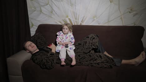 small daughter with her father watching interesting film and eating apple