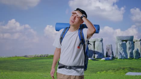 asian male hiker with mountaineering backpack hand forehead smiling and looking distance while traveling in stonehenge