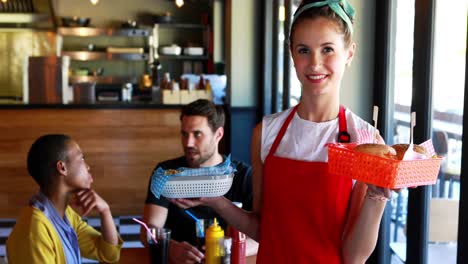 waitress holding burger and french fries in tray