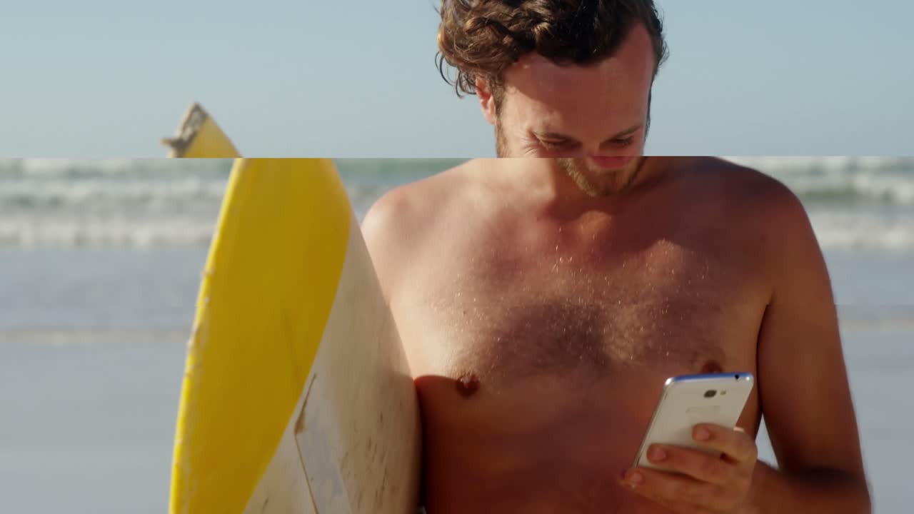 Uomo che usa il cellulare mentre tiene la tavola da surf in spiaggia