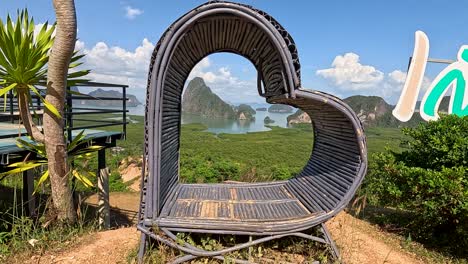 a heart-shaped structure frames a stunning view of phuket's lush landscape and limestone formations under bright daylight