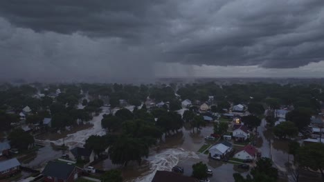 nubes oscuras de tormenta se ciernen sobre un vecindario suburbano inundado, la lluvia cae sobre casas y árboles parcialmente sumergidos, creando una escena de devastación generalizada.