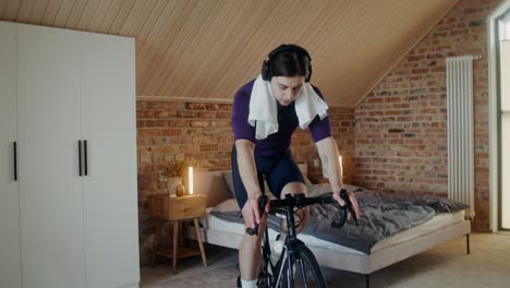 hombre trabajando en una máquina de ciclismo interior en el dormitorio
