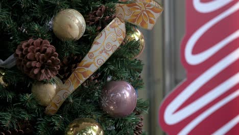 christmas dry pine cones and gold balls ornament decorations are seen hang from a decorated christmas pine tree