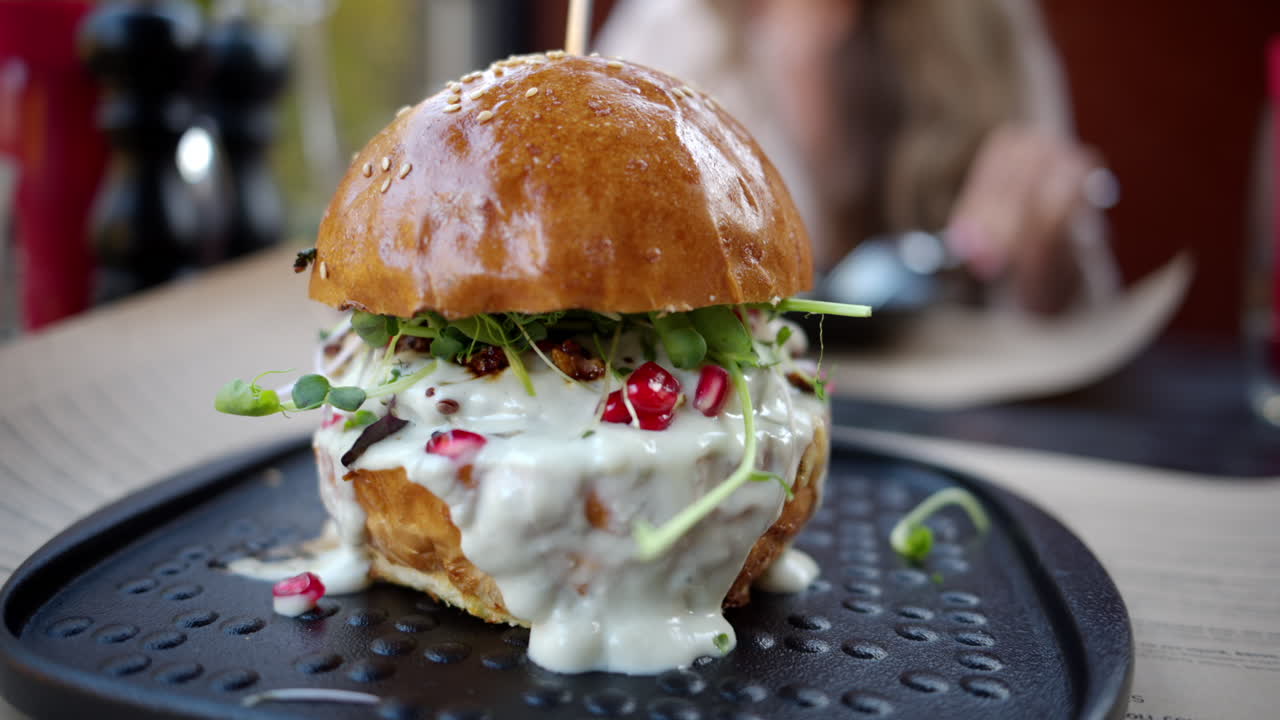 Close up of a burgher with white cheese sauce and pomegranate