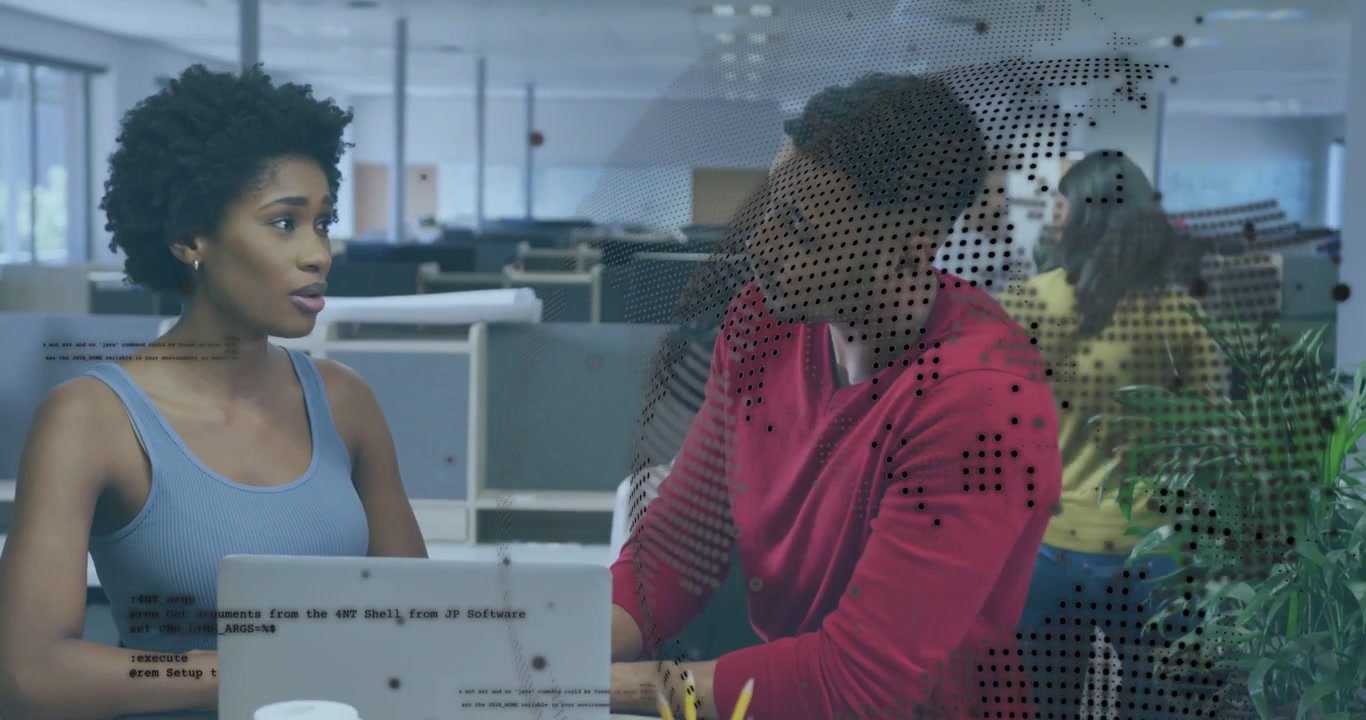 Seated woman pointing at laptop to review standing man leaning reaching tech overlay showing code
