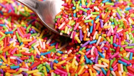 a spoon scoops vibrant sprinkles from a pile