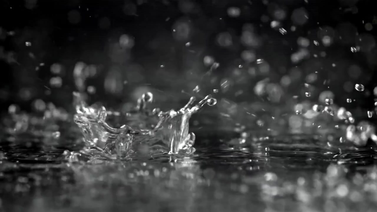 Wassertropfen fallen und spritzen in Zeitlupe auf eine dunkle Oberfläche
