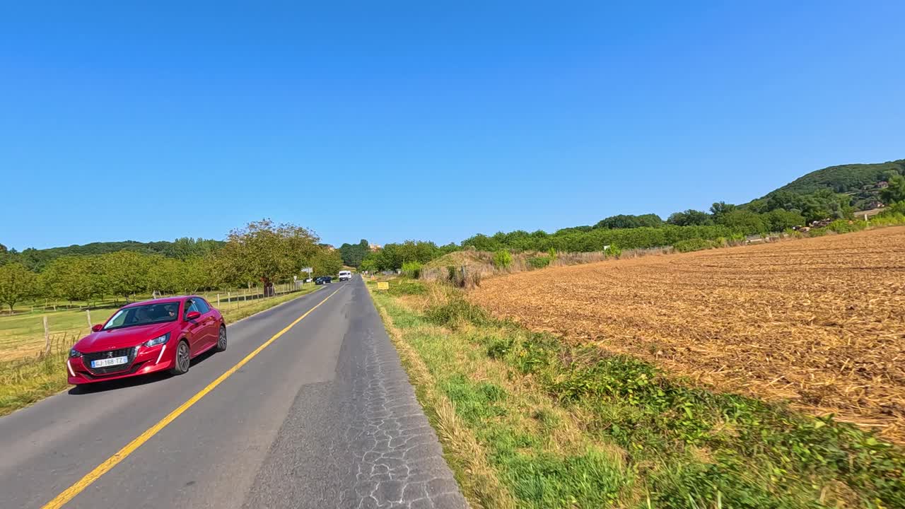 빨간 차가 보르도 지방의 시골 도로를 따라 이동합니다.