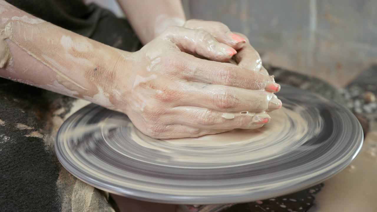 un alfarero enseña a una mujer a hacer platos de arcilla. un hombre toma las manos de una mujer