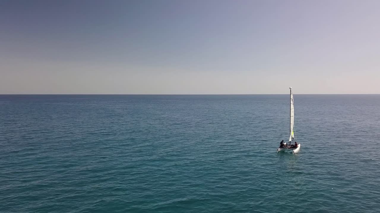 vista aérea del velero solitario navegando en el agua del océano con la cálida luz del atardecer