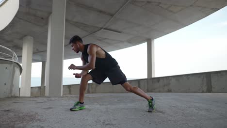 athlete in sportswear warms up on a city parking garage, stretching legs