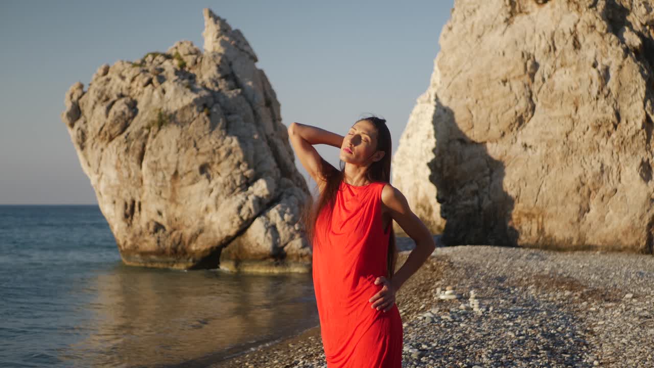 Lonely Sexy Woman in Red Dress Standing on Beach by Mediterranean Sea on Golden Hour Sunlight, Full Frame