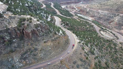 Truck-and-cars-drive-down-steep-winding-road-toward-river-in-Arizona-canyon