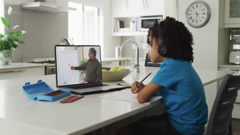 Niño-Afroamericano-Usando-Una-Computadora-Portátil-Para-Videollamada-Con-Un-Maestro-En-La-Pantalla